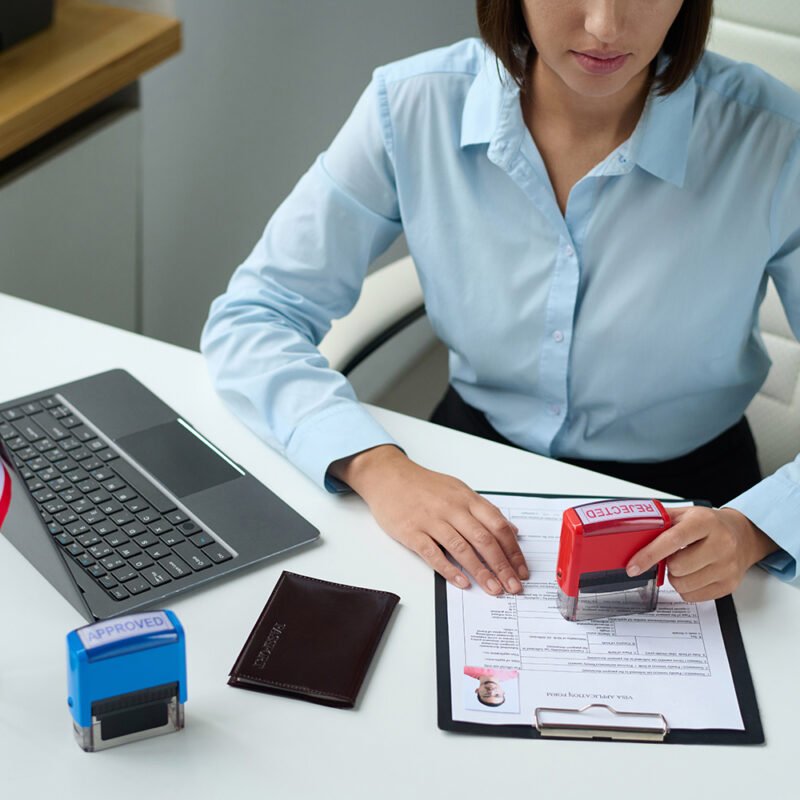 High angle view of professional specialist rejecting visa for tourist putting stamp on document